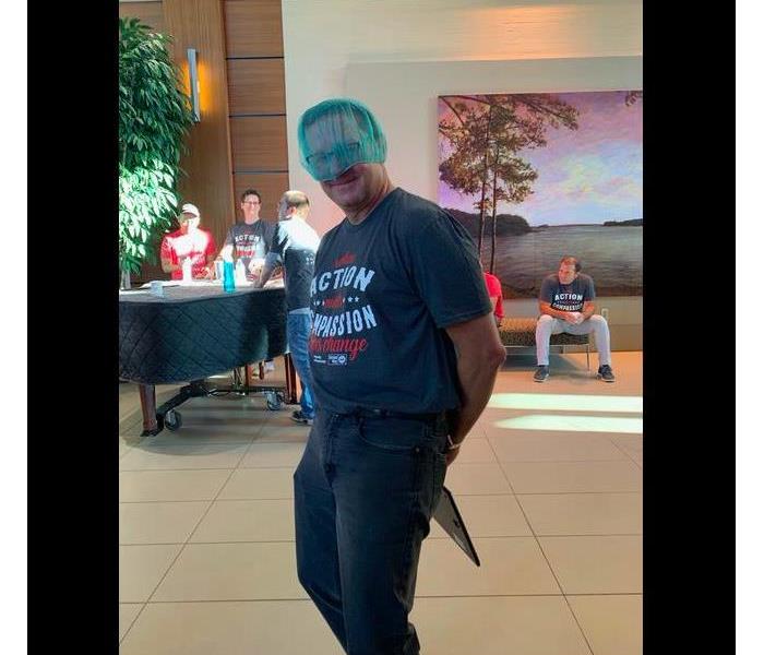 Team member posing with his blue hair net on his head. He is wearing blue jeans and a t-shirt.