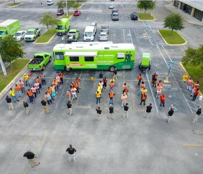 Team members of SERVPRO lined up in a parking lot, green trailer parked